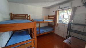 a room with three bunk beds and a window at Casa 2 minutos a pé da Praia de INDAIÁ in Bertioga