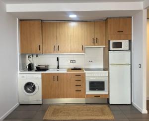 a kitchen with white appliances and wooden cabinets at El Sueño De Albarracín IV in Albarracín