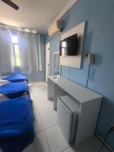 a room with three beds and a tv on the wall at Hotel Portugal in Macaé