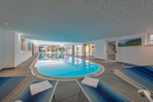 a large swimming pool in a building with benches at Garni Hotel Sonnleitenhof in Caldaro