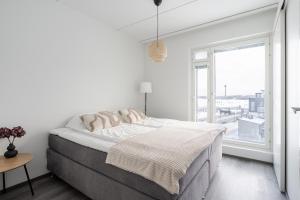 a white bedroom with a large bed and a window at Luxurious Penthouse - Hot Tub & Sauna in Tampere