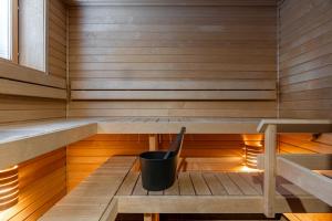 a sauna with a bucket sitting on a wooden bench at Luxurious Penthouse - Hot Tub & Sauna in Tampere