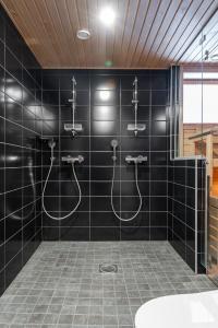 a black tiled bathroom with two showers and a sink at Luxurious Penthouse - Hot Tub & Sauna in Tampere