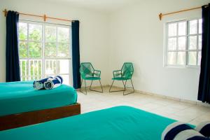 a room with two beds and two chairs and windows at Balu Hotel in Isla Mujeres +103 photos