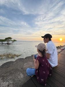 a man and a little girl sitting on a dock near the water at Gili Glow Homestay in Gili Trawangan