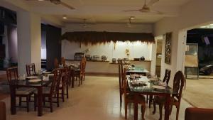 a dining room with tables and chairs and a kitchen at Hotel Ruwan in Kataragama