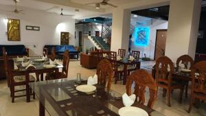a dining room with tables and chairs and a staircase at Hotel Ruwan in Kataragama