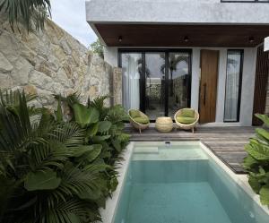a swimming pool in front of a house at Rahya Villas Complex by Iji in Uluwatu