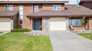 a house with two white garage doors in a yard at Peaks & Par in Red Lodge