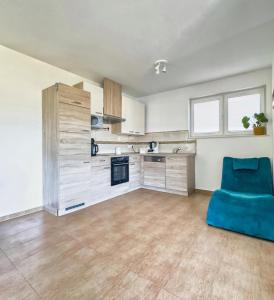 a living room with a blue chair and a kitchen at Ferienwohnung in Neudenau