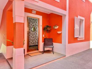 an orange room with a chair in front of a door at The Pink Villa - Holidays in Madeira Island in Caniço