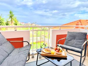a balcony with two chairs and a tray of fruit on a table at The Pink Villa - Holidays in Madeira Island in Caniço