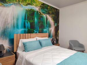 a bedroom with a waterfall mural on the wall at Paraíso Verde in Algarvia