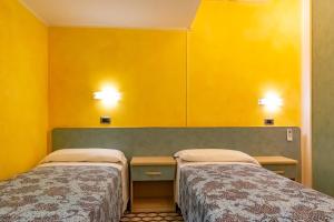 two beds in a room with yellow walls at Jans e Gracy - Appartamenti e camere in Gabicce Mare +31 photos