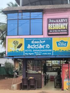a restaurant with signs on the side of a building at Aarvi Residency in Māvalli