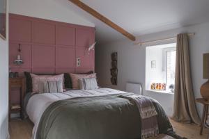 a bedroom with a large bed with a pink headboard at Maison d'hôtes La bien-Aimée in Montrevault