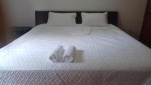 two pairs of slippers sitting on a white bed at Hacienda Torcoroma in Bucaramanga