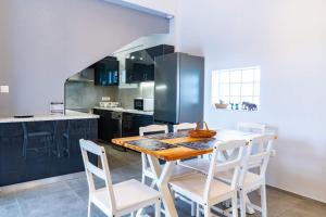a kitchen with a wooden table and white chairs at Casa Anavyssos in Anavyssos