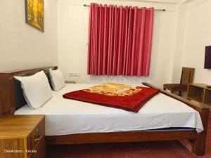 a bedroom with a bed with a red curtain at Rose Cottage in Devikolam +7 photos