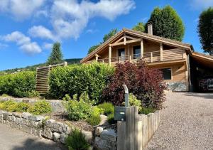 a wooden house with a fence in front of it at Chalet Les Roitelets 5 étoiles avec jacuzzi sauna in Gérardmer