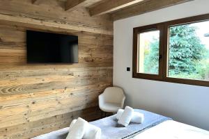 a bedroom with a wood accent wall with a television at Chalet Les Roitelets 5 étoiles avec jacuzzi sauna in Gérardmer