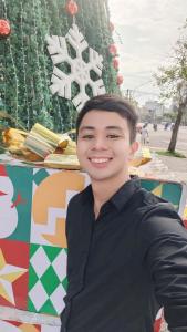 a young man standing in front of a christmas tree at Spa Ý Phát in Ấp Yên Thượng