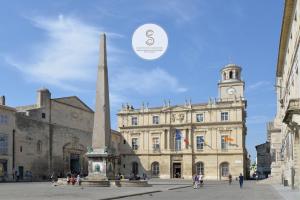 a building with a monument in front of it with a clock tower at Le Cloître Arles Centre in Arles