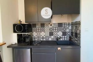a kitchen with black and white tile on the wall at Le Cloître Arles Centre in Arles +4 photos