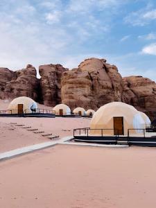 a group of tents in the desert with rocks at ULORA Luxury Camp in Wadi Rum