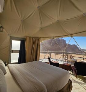 a bedroom with a bed and a view of the desert at ULORA Luxury Camp in Wadi Rum