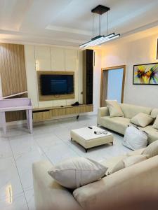 ein Wohnzimmer mit Sofas, Fernseher und Klavier in der Unterkunft Stan - Haven Apartments ASOKORO in Asokoro