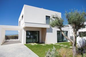 a white house with a green yard at Ocean View Pool Villa Family & Surf in Ericeira in Ribamar