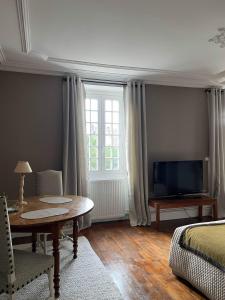 a bedroom with a bed and a table and a tv at La Chambre d'Adèle in Louhans