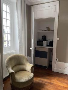 a living room with a chair and a microwave at La Chambre d'Adèle in Louhans