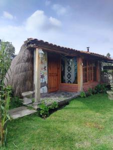 a small house with a thatch roof at Wasi Andina Lodge in Latacunga