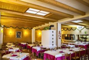 ein Esszimmer mit Tischen und Stühlen mit rosa Tischdecke in der Unterkunft Hotel Al Pelmo in Pieve di Cadore