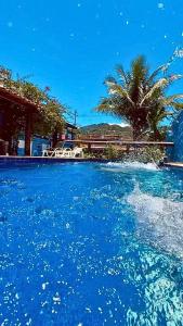 a pool of blue water with a palm tree in the background at Nalu Suítes Maresias in Maresias