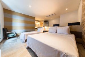 um quarto de hotel com duas camas e uma cadeira em Boutique Hotel SB Yeouido em Seul