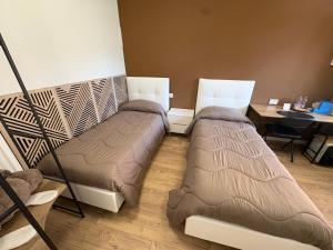two beds sitting in a room with a desk at Elco Rooms Malpensa in Lonate Pozzolo