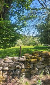 a stone wall in front of a field at Cwt Cen y Coed in Llanferres