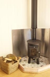 a wood stove sitting in a room with a basket at Cwt Cen y Coed in Llanferres