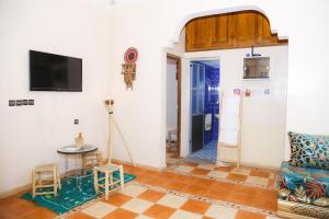 a living room with a tv and a table at Cozy Host House with 2 air conditioned rooms in Er Rachidia