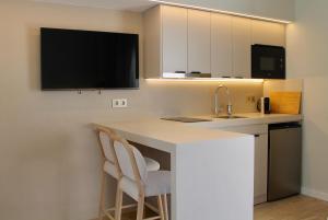 a kitchen with a sink and a counter with two chairs at Makāi Bungalows in Playa del Aguila