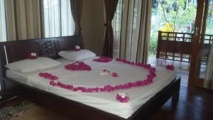 Una cama con un corazón hecho de flores rosas en Khoo Villa en Senggigi 