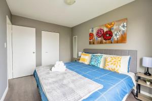 a bedroom with a bed with blue sheets and a painting at Charming Newly Renovated Condo - Glenview West in Hamilton