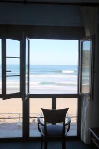 
a chair sitting in front of a window overlooking the ocean at Hotel Ribadesella Playa in Ribadesella
