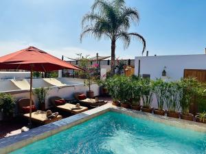 a swimming pool with tables and chairs and an umbrella at Riad Jardin Des Sens & Spa in Marrakesh