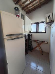 a kitchen with a white refrigerator and a table at Pousada da Tom-Ubatuba Perequê-Açu in Ubatuba