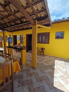 a patio with yellow walls and a table and chairs at Pousada da Tom-Ubatuba Perequê-Açu in Ubatuba