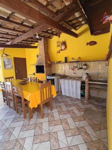 a kitchen with yellow walls and a table and chairs at Pousada da Tom-Ubatuba Perequê-Açu in Ubatuba